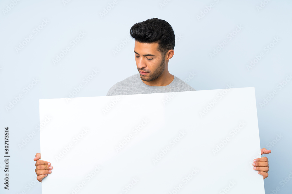 Young handsome man over isolated background holding an empty white placard for insert a concept Young handsome man over isolated background holding an empty white placard for insert a concept