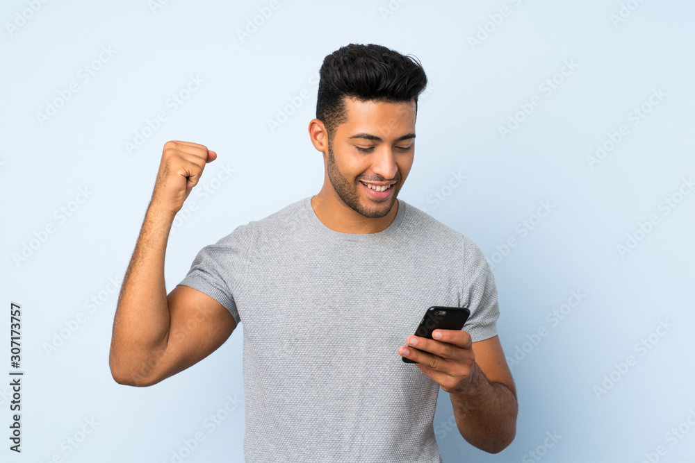 Young handsome man over isolated background using mobile phone