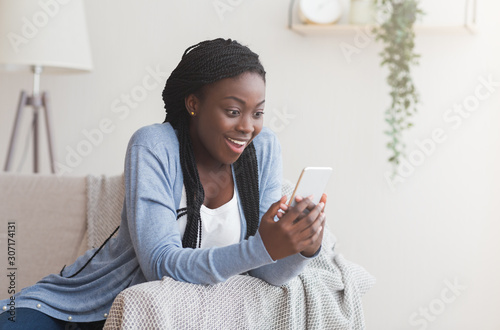 Excited black woman receiving good news online in smartphone