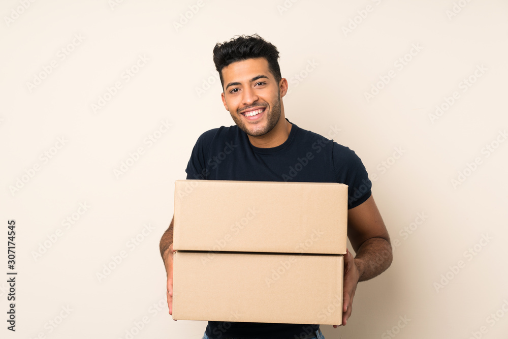 Young handsome man over isolated background holding a box to move it to another site Young handsome man over isolated background holding a box to move it to another site