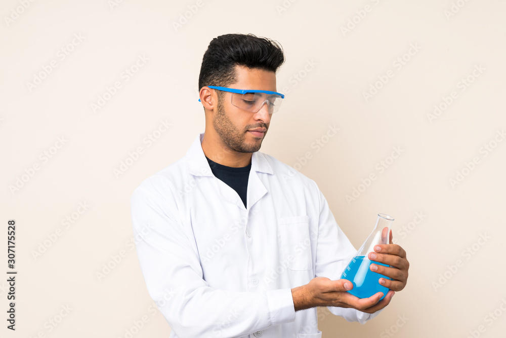 Young handsome man over isolated background with a scientific test tube Young handsome man over isolated background with a scientific test tube