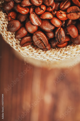 Coffee beans closeup in burlap bag on wooden background. Soft contrast. Aromatic roasted coffee beans.