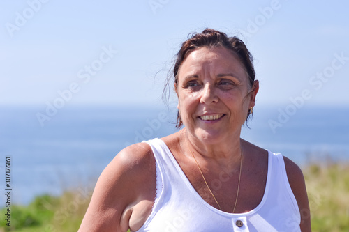 Middle age woman portrait by the sea side in summer, smiling