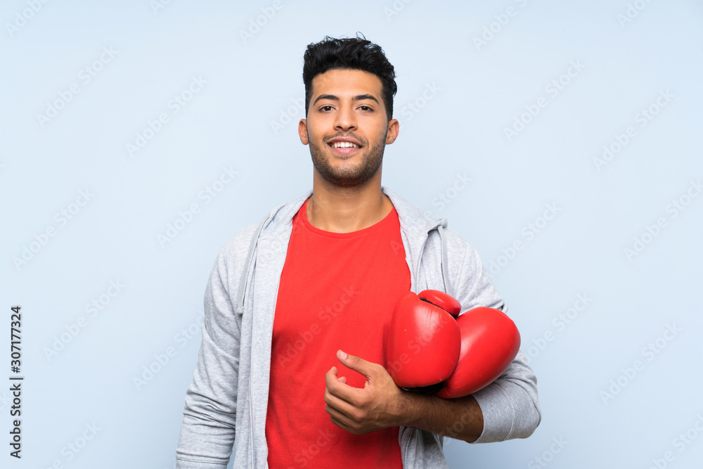 Sport man with boxing gloves over isolated blue wall Sport man with boxing gloves over isolated blue wall