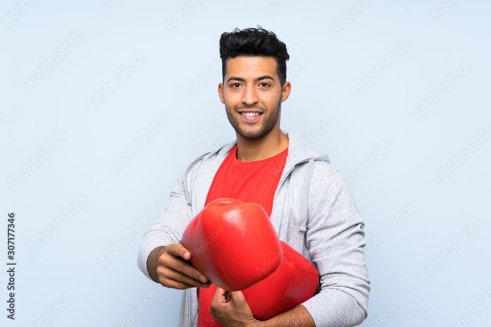 Sport man with boxing gloves over isolated blue wall Sport man with boxing gloves over isolated blue wall
