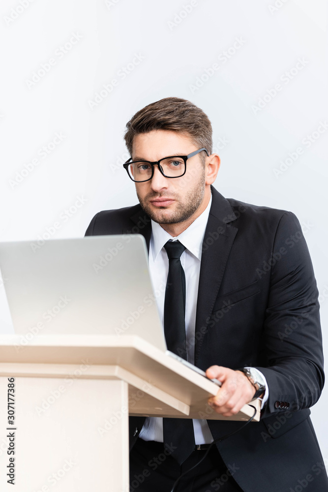 scared businessman in suit standing at podium tribune and looking at camera during conference isolated on white scared businessman in suit standing at podium tribune and looking at camera during conference isolated on white