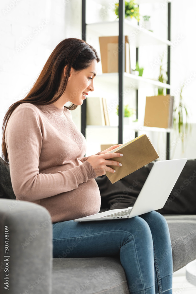 pregnant woman holding book while having online consultation with doctor on laptop at home pregnant woman holding book while having online consultation with doctor on laptop at home