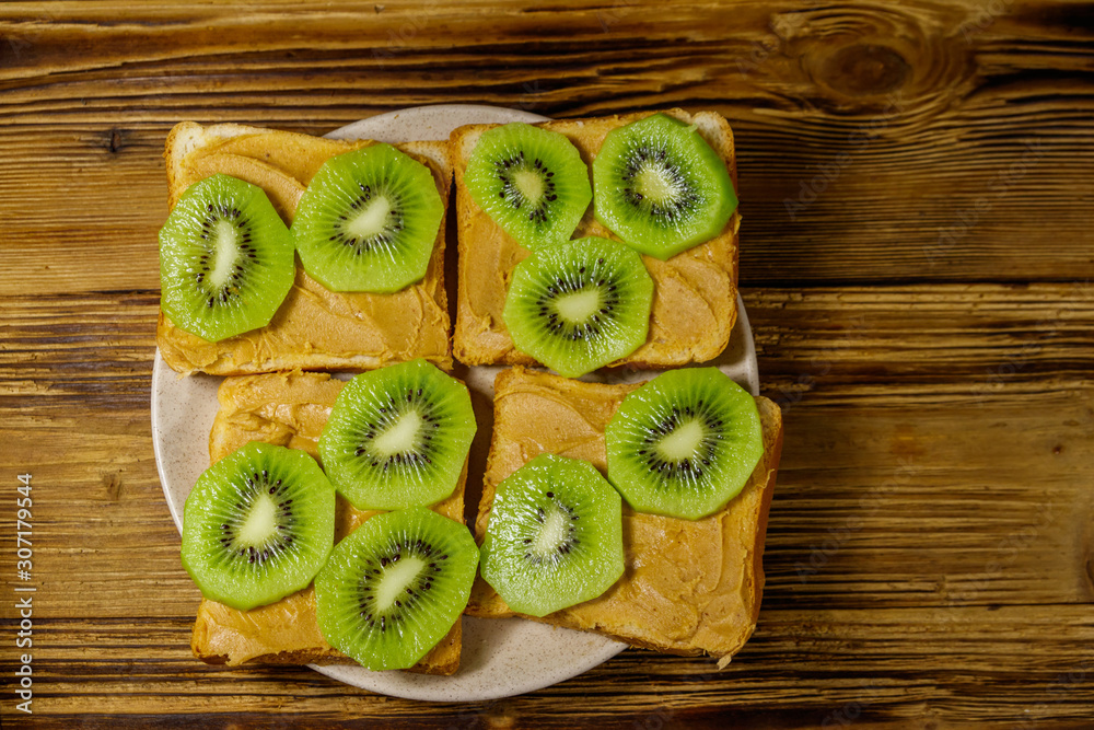 Tasty sandwiches with peanut butter and kiwi fruits on wooden table. Top view Tasty sandwiches with peanut butter and kiwi fruits on wooden table. Top view