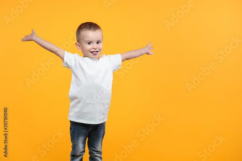 Kid boy wearing white t-shirt with space for your logo or design over yellow background