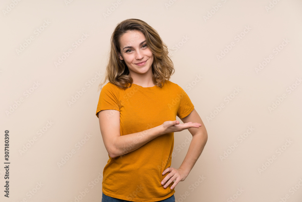 Young blonde girl over isolated background presenting an idea while looking smiling towards Young blonde girl over isolated background presenting an idea while looking smiling towards