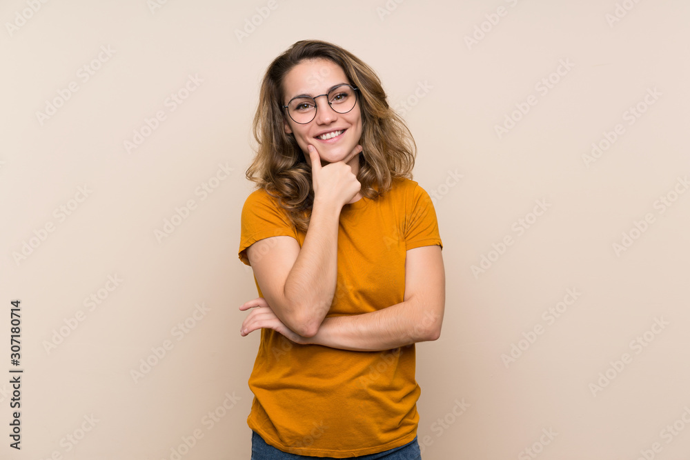 Young blonde girl over isolated background with glasses and smiling Young blonde girl over isolated background with glasses and smiling