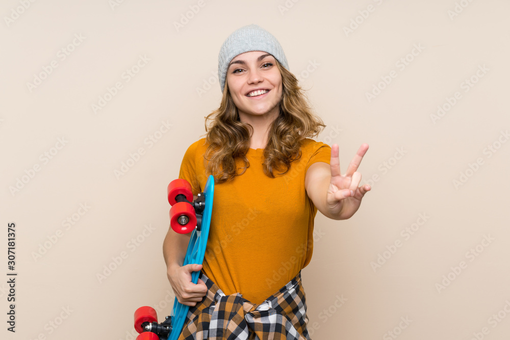 Young skater blonde girl over isolated background smiling and showing victory sign Young skater blonde girl over isolated background smiling and showing victory sign