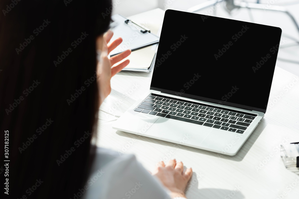 cropped view of doctor having online consultation with patient on laptop in clinic
