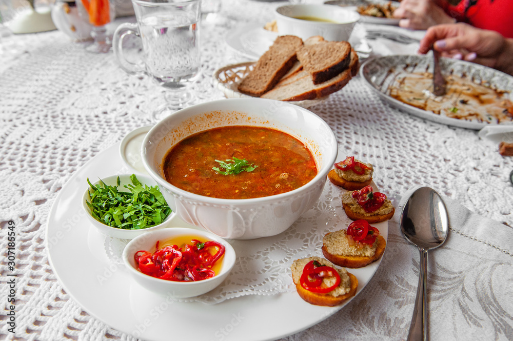 Tomato soup with pepper, parsley spices in a white plate in a restaurant serving with a set of canapes. Close up Tomato soup with pepper, parsley spices in a white plate in a restaurant serving with a set of canapes. Close up