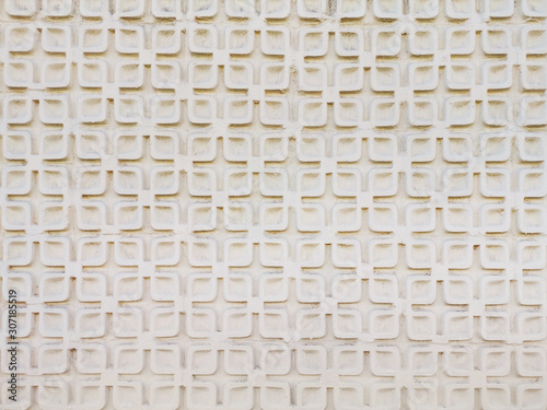 Simple geometric stucco work on an exterior wall. Light beige plaster. Architectural detail. Symmetric pattern. Soft light