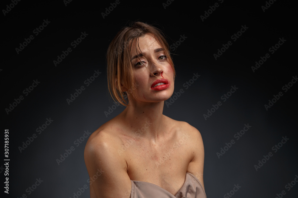 Emotional dramatic portrait of a young woman with traces of violence on her face. The concept of the problem of violence against women. Emotional dramatic portrait of a young woman with traces of violence on her face. The concept of the problem of violence against women.