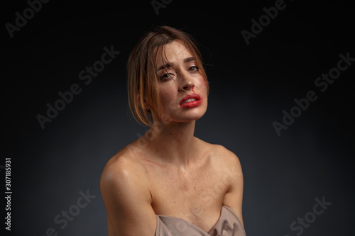 Emotional dramatic portrait of a young woman with traces of violence on her face. The concept of the problem of violence against women.