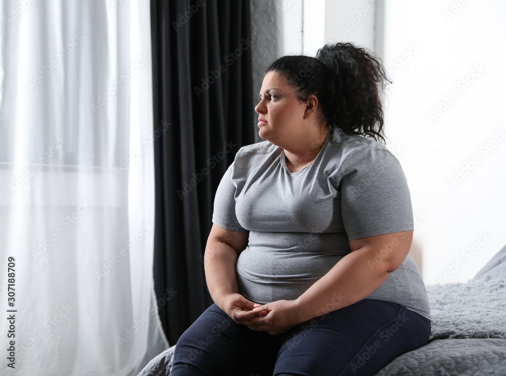 Depressed overweight woman on bed at home Depressed overweight woman on bed at home