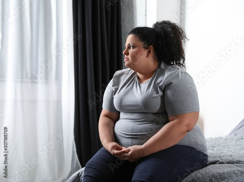 Depressed overweight woman on bed at home photo