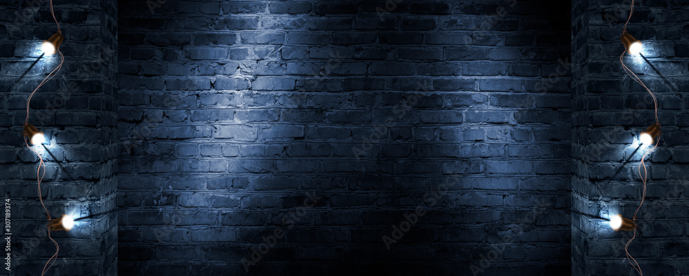 Obraz premium Dark street, old brick wall decorated with night lanterns. Empty street scene, neon light. Night view, blurred abstract bokeh light.
