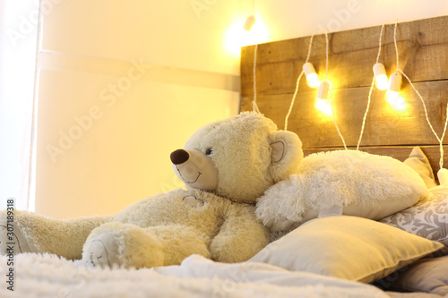 white bed with teddy bear with christmas garland light decoration photo