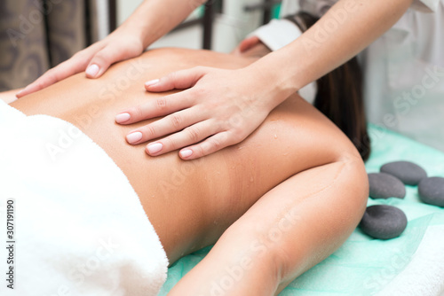 A young girl enjoys spa treatments. Hands of a massage therapist, beautician make massage.