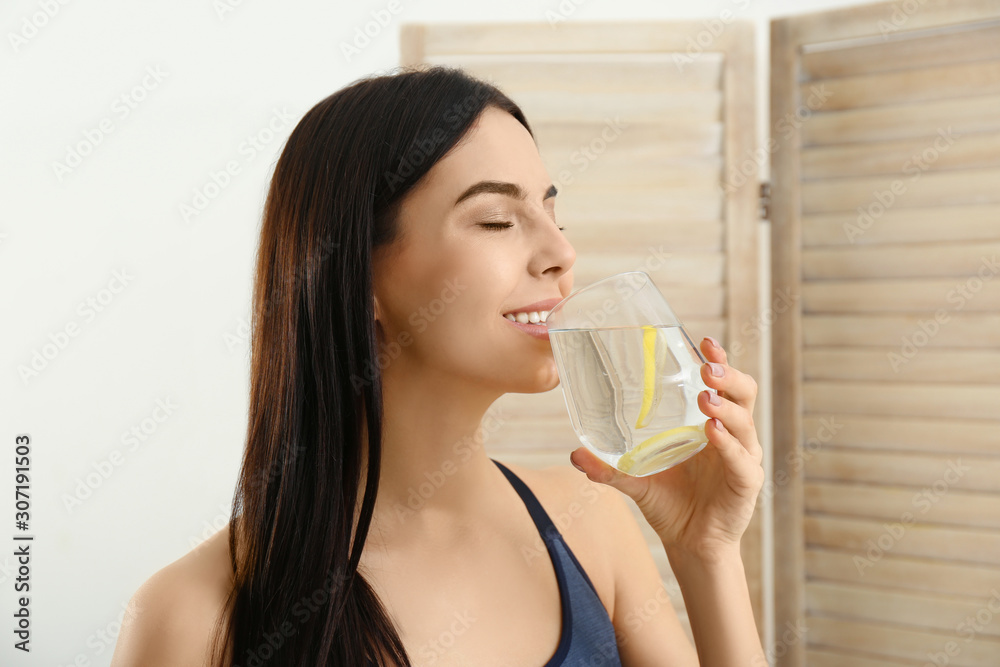 Beautiful young woman drinking fresh lemon water indoors Beautiful young woman drinking fresh lemon water indoors