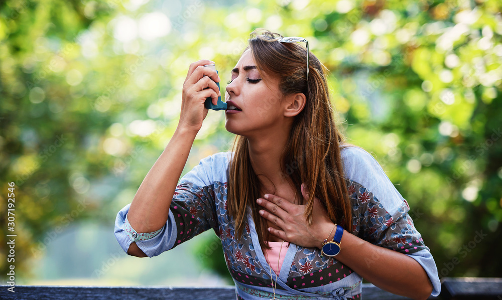 Young woman treating asthma with inhaler. Health care concept Young woman treating asthma with inhaler. Health care concept