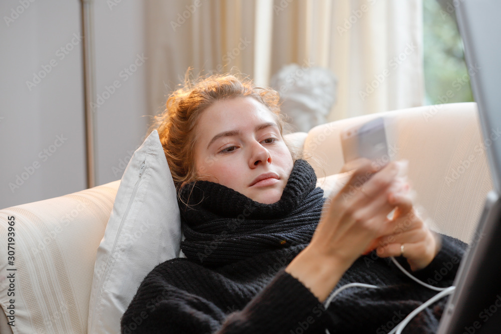 Young attractive law student on a sofa, using notebook and smartphone.