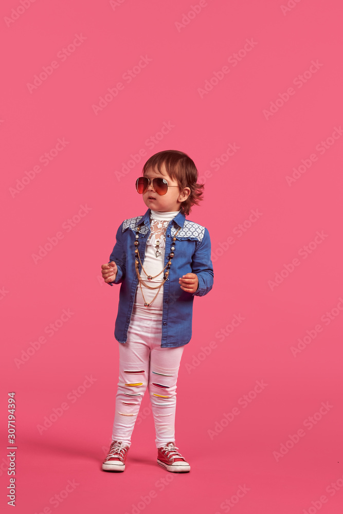 funny little girl in a beach hat and sun glasses on a pink background, studio shooting funny little girl in a beach hat and sun glasses on a pink background, studio shooting