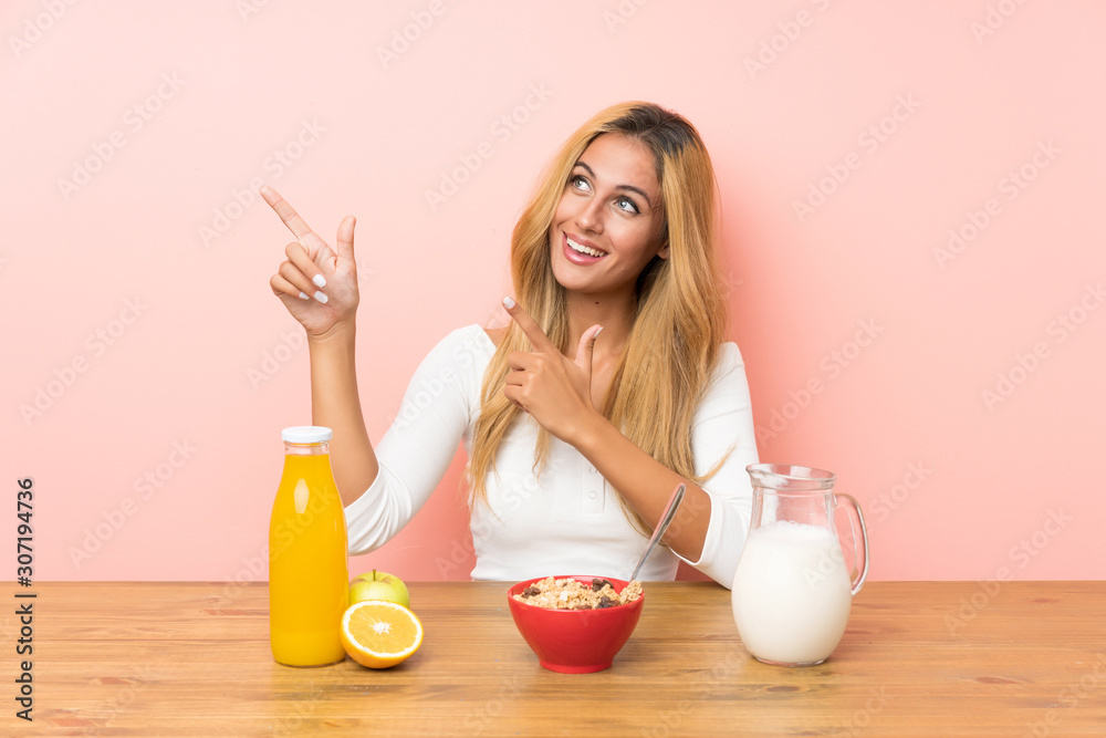 Young blonde woman having breakfast milk pointing with the index finger a great idea Young blonde woman having breakfast milk pointing with the index finger a great idea