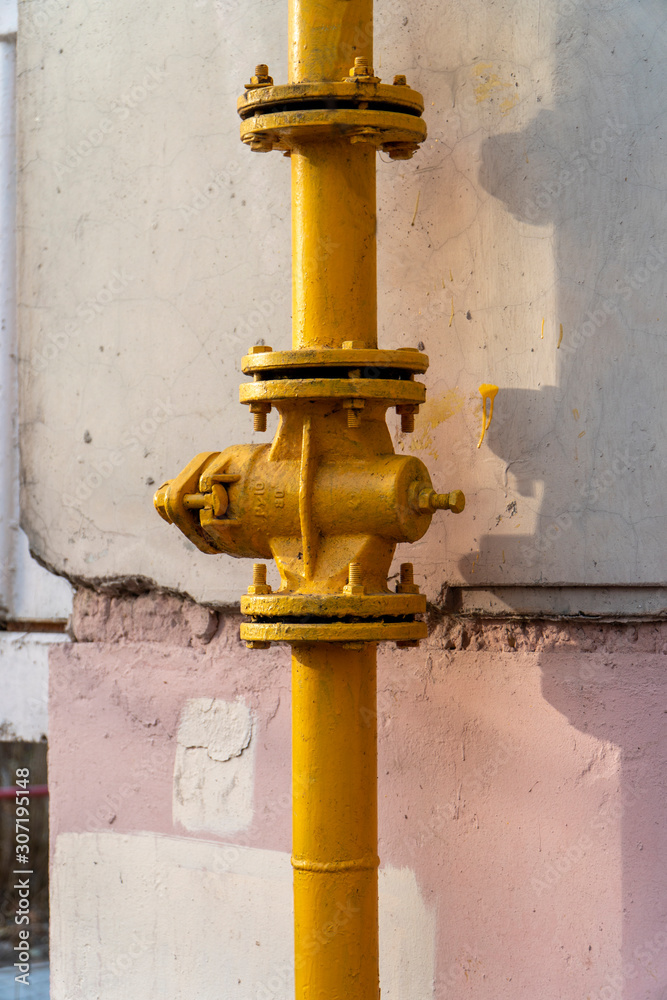 Yellow gate valve with flanges on the vertical gas supply pipe Yellow gate valve with flanges on the vertical gas supply pipe