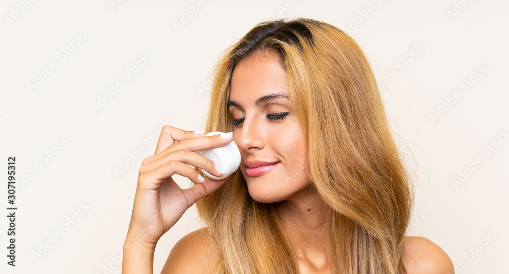 Young blonde woman with moisturizer over isolated background Young blonde woman with moisturizer over isolated background