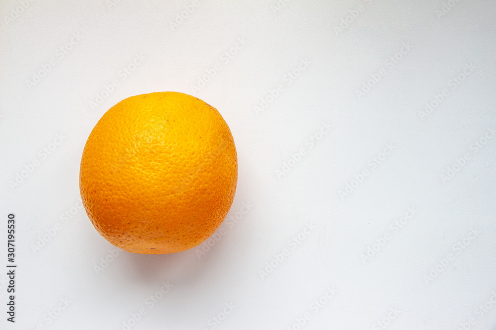 A single orange on a white background to the left. Right space for text. Top view, flat lay A single orange on a white background to the left. Right space for text. Top view, flat lay