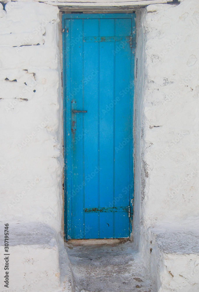 Santorini Greece scene of light blue wooden door in white stone house