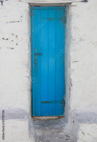 Santorini Greece scene of light blue wooden door in white stone house