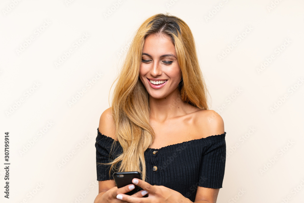 Young blonde woman with a mobile over isolated background Young blonde woman with a mobile over isolated background