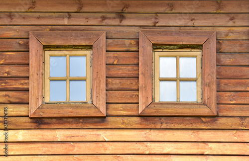Two small wooden square windows in a plank wall