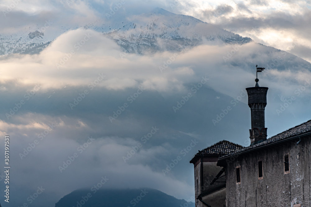 Italian tower against mountain and clouds