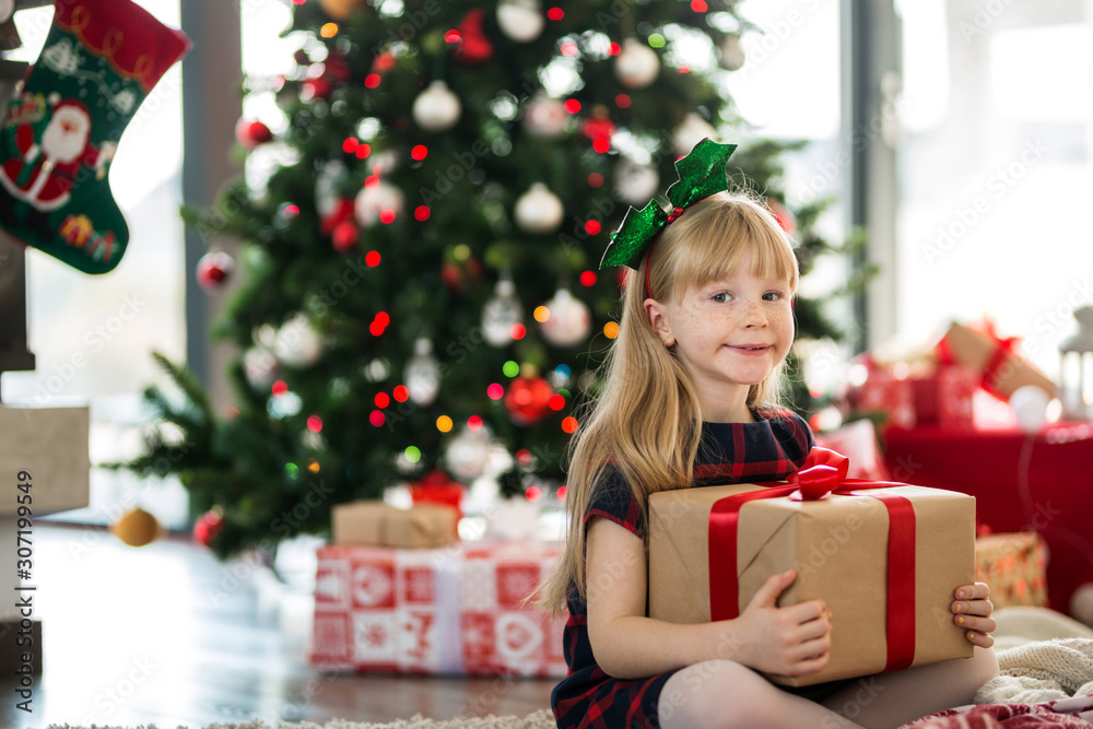 Young girl sitting on the floor holding christmas gift