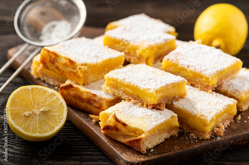 Homemade lemon bars with shortbread crust, on wooden background. 