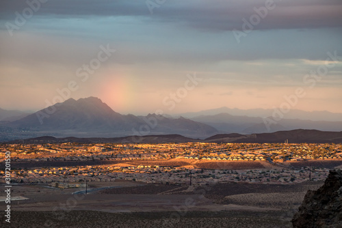 USA, Nevada, Clark County, Henderson. A sunset, sun dog rainbow, and Frenchman Mountain over the Sun City Anthem planned community neighborhood south of Las Vegas.