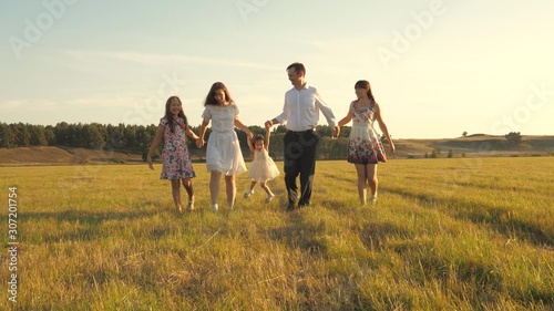 concept of a happy family. Children and mom are playing in meadow. mother and little daughter with sisters walking in park. Happy young family with child walking on summer field. happy family concept