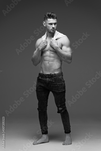 a young man with a beard in a t-shirt. Stylish Male portrait on a gray background. Black and white photo. male Studio portrait. Fitness model.