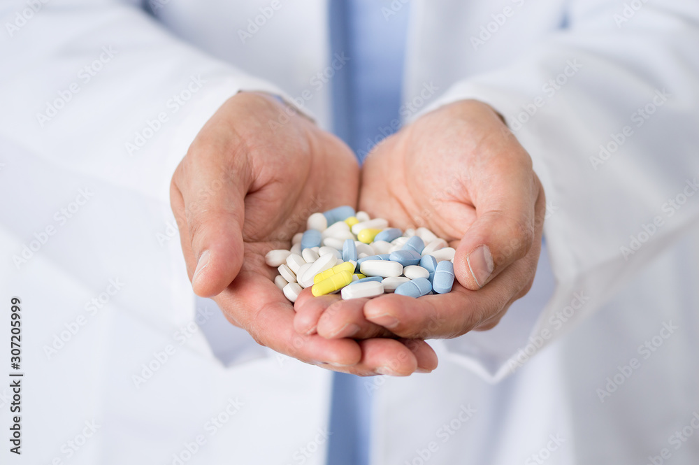 Closeup shot of an unidentifiable male doctor holding a variety of pills in her hands Closeup shot of an unidentifiable male doctor holding a variety of pills in her hands