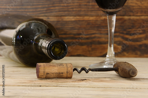 Corkscrew and cork on the background of a bottle and wine glass for wine
