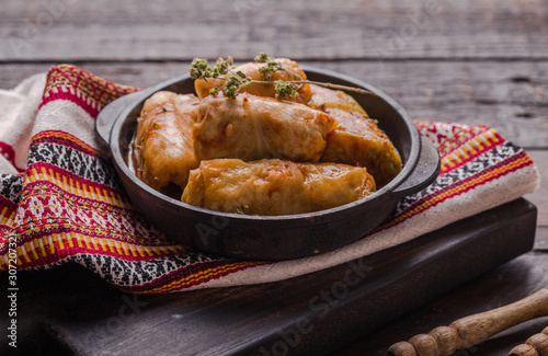 Meat in cabbage rolls in a black pan with  sauce on wooden background.  Asian cuisine top view