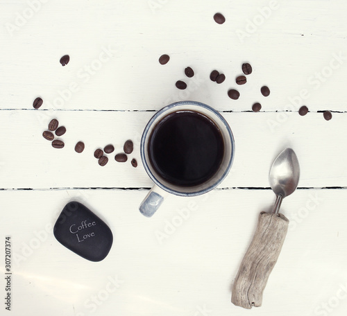 cup of coffee, coffee seeds and spoon on the table