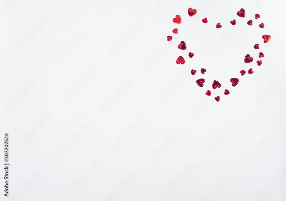 Valentines decoration of red confetti in shape of  hearts on white background. Top view. Copy space. Flat lay