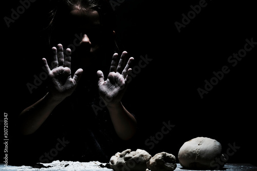 Little cute girl chef cooking with white flour on black background